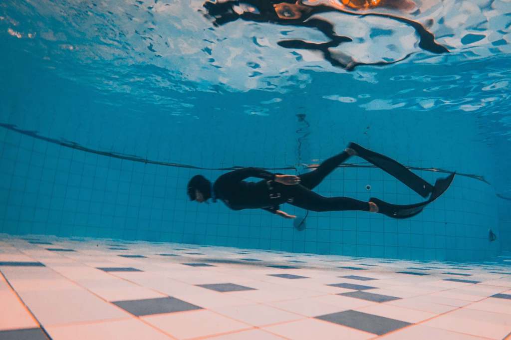 Free diver holding breath while swimming underwater in open ocean