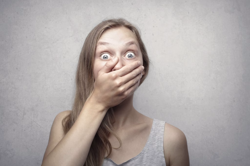 Woman covering her mouth while laughing nervously during a tense moment, illustrating why do I laugh when nervous